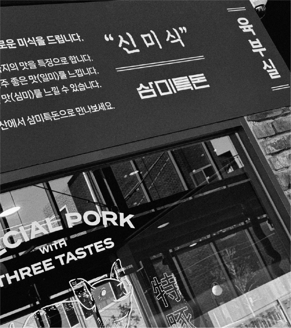 Sammi Teukdon store exterior signage and reflected brand message on glass. The strong black and white contrast conveys the brand's sophisticated and confident image. Sammi Teukdon store exterior with signage and reflected brand text on glass
