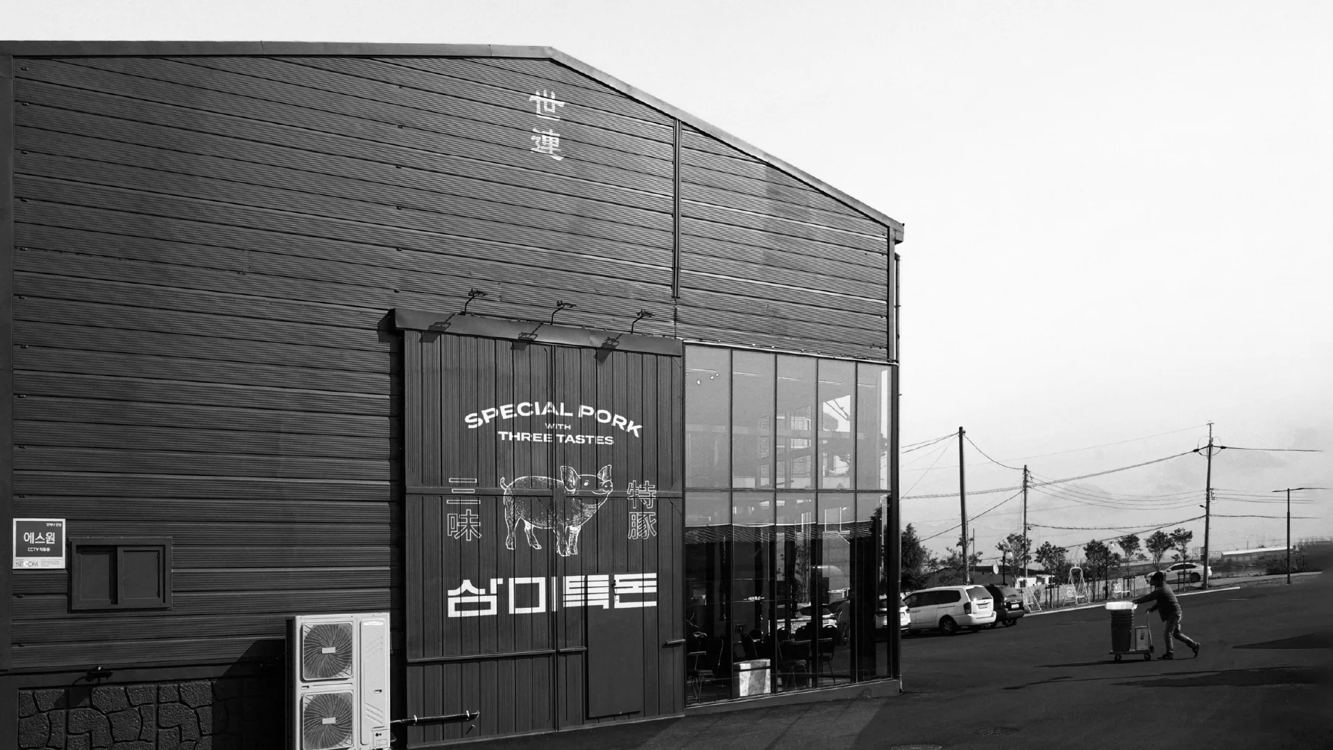 Exterior view of the Sammi-Teukdon brand building, showcasing its identity where tradition meets modernity. The signage design harmonizes with the surroundings. Black and white photo of a modern building with Sammi-Teukdon signage.